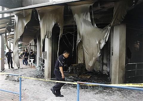 A Kuala Lumpur police officer inspects the damage to the Metro Tabernacle Church which was destroyed by a fire bomb in the Kuala Lumpur suburb of Desa Melawati,08 Jan 2010 (Photo AP)