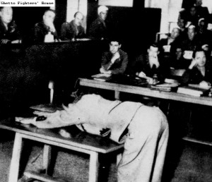 A witness in the war crimes trial of the Dachau camp staff, demonstrating to the panel of judges the method of flogging used in the Nazi camp. (Source: Ghetto Fighter's Archive, Catalog No.: 25956)